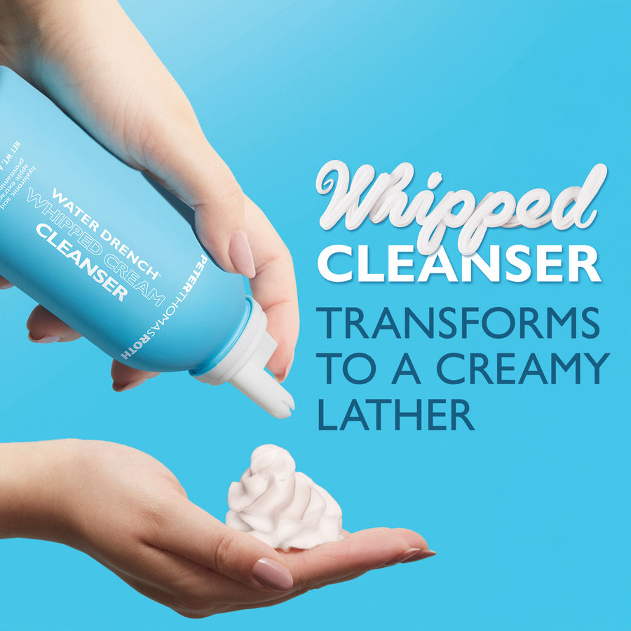 Blue cylindrical cleanser bottle being held with white whipped cream product dispensed into an open hand against blue backgro
