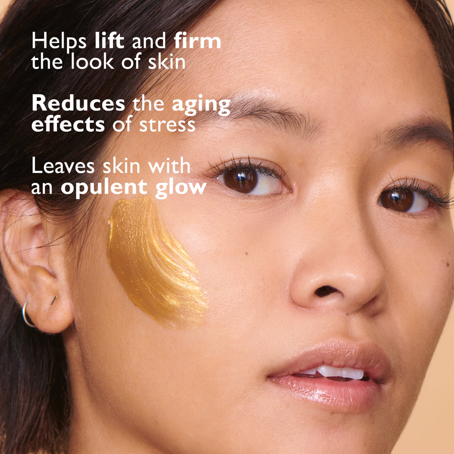 Gold-colored face mask applied to cheek and temple area of person with dark hair and brown eyes.