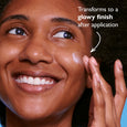 Person with medium skin tone applying moisturizer to cheek, showing hydrated, dewy complexion.