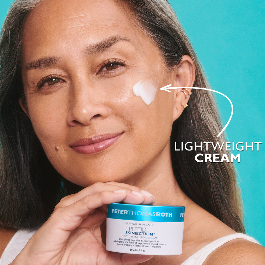 Woman holding a blue and white skincare jar with lightweight cream applied on her cheek against turquoise background.