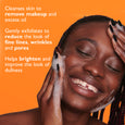 Woman applying foamy cleansing gel to face against orange background.