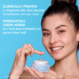Woman with dark hair holding an open jar of pale purple jelly moisturizer against a bright blue background.