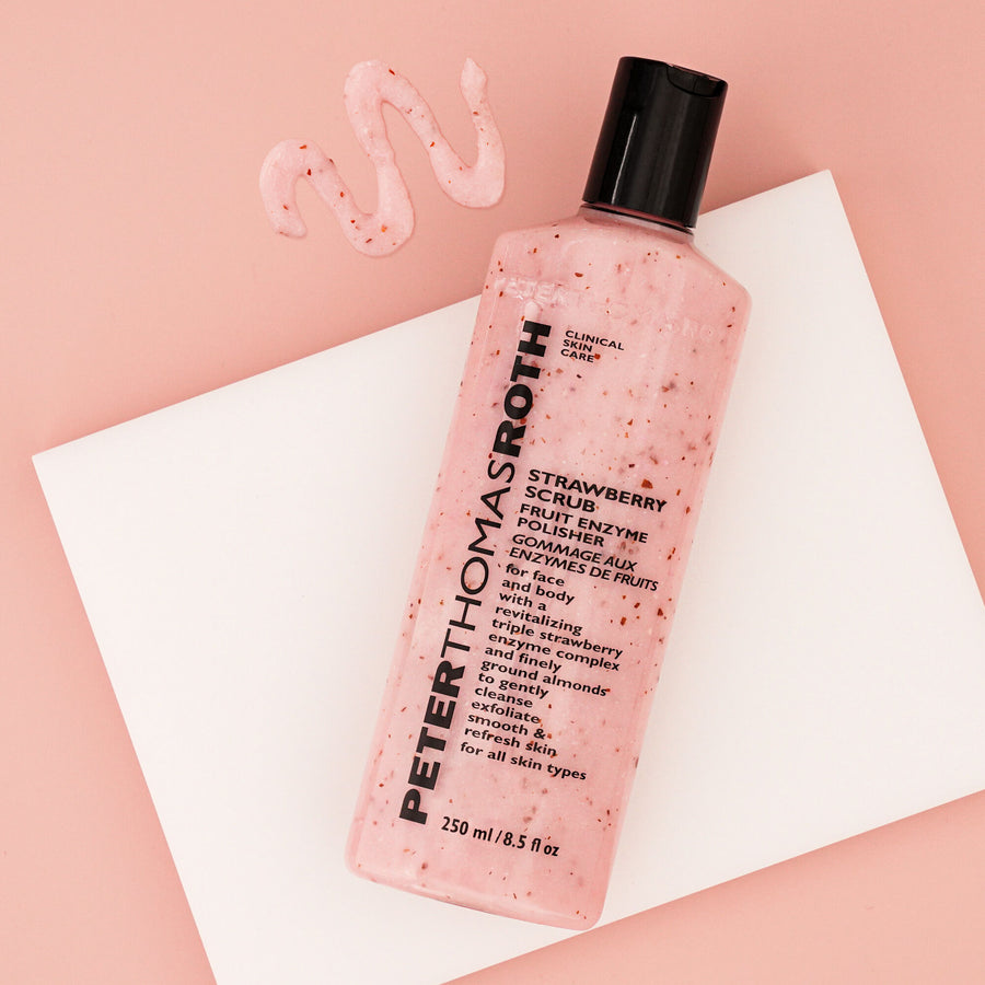 Pink strawberry scrub with visible red particles in a 250 ml bottle with black cap, displayed with product swatches on pink b