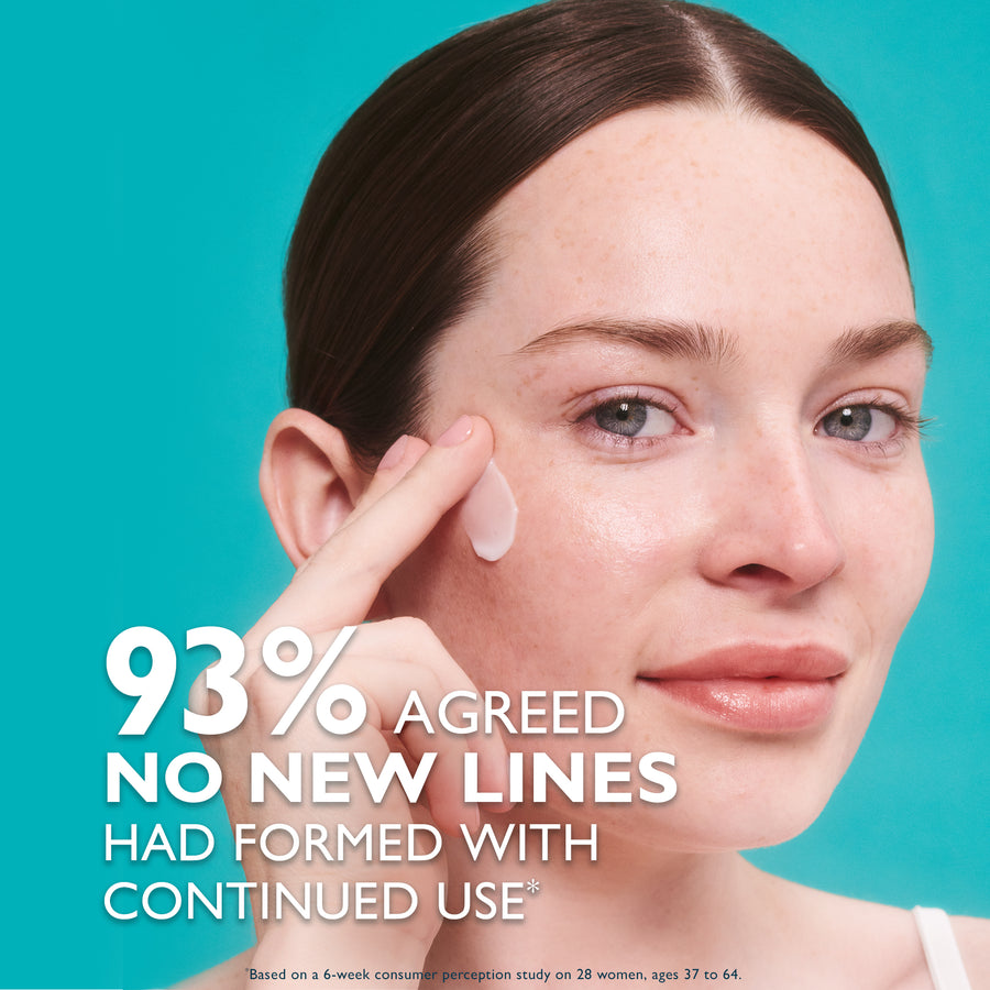Woman applying clear serum to cheek against turquoise background.