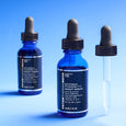 Three blue glass dropper bottles of Retinol Fusion PM Night Serum with black caps against a blue background.