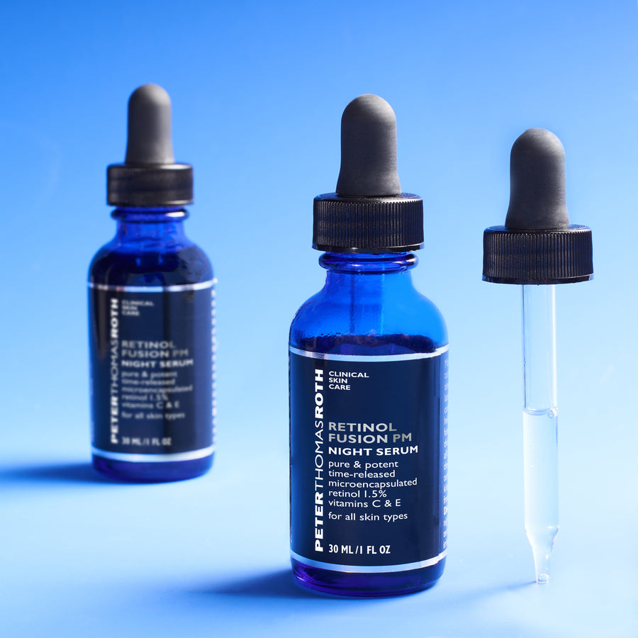 Three blue glass dropper bottles of Retinol Fusion PM Night Serum with black caps against a blue background.