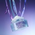 Clear jar of Ultimate Solution 5 multitasking moisturizer with white cream and colorful liquid streams pouring down against p