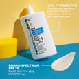 White pump bottle of sunscreen serum with blue label next to a white cream swatch, yellow cup, and yellow background.
