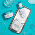 White and turquoise Peter Thomas Roth Peptide Skinjection skincare products displayed on turquoise background with glass cont