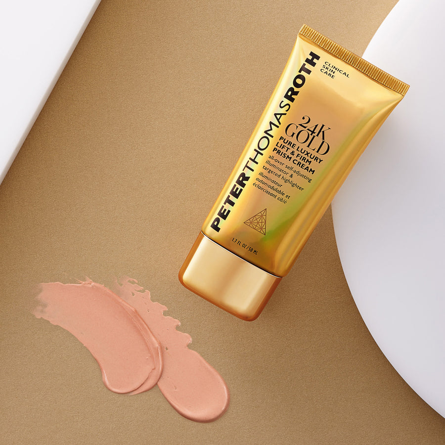 Gold tube of Peter Thomas Roth 24K Gold Prism Cream with beige applicator cap and pink cream swatches on tan background.
