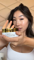 Gold-trimmed jar of hydra-gel eye patches with white label held by person's hand near face.