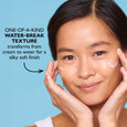 Person with hands framing face demonstrating skincare product application against blue background.